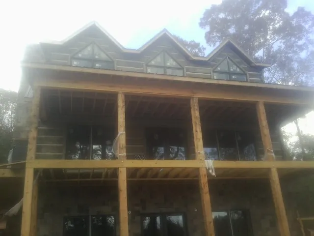 Dormers and porch framing on a large log home under construction — Roof Coating work by our crew in Manhasset