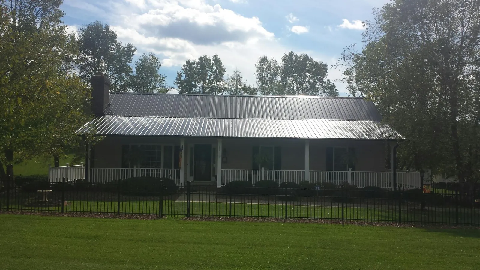 Gray metal roof on a brick ranch with a full width front porch — Gutter Guard Installation work by our crew in Manhasset