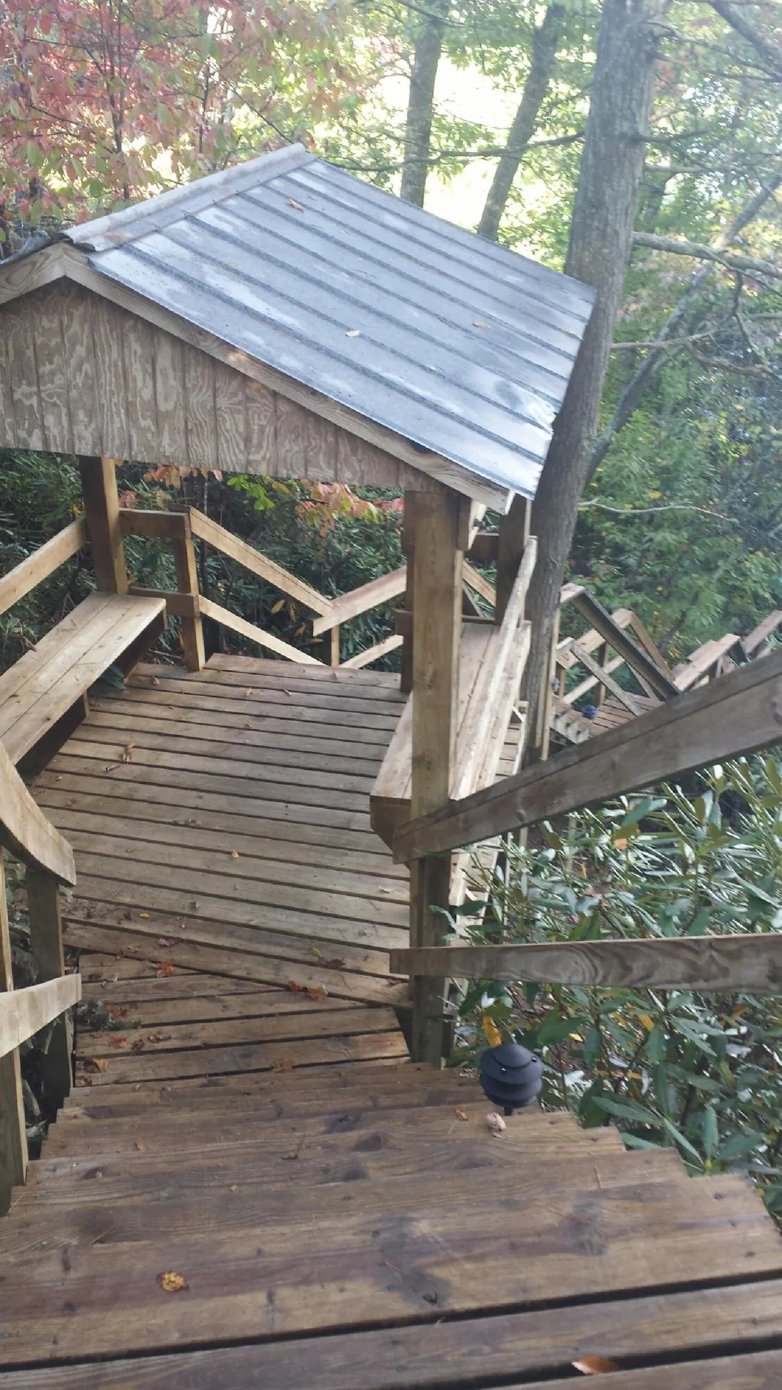 Metal roofed shelter over wooden steps on a wooded walkway — Skylight Repair & Installation work by our crew in Manhasset