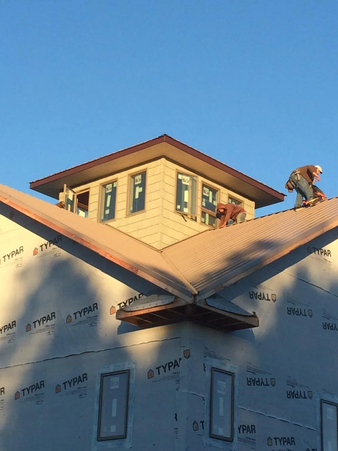 Roofers working around a rooftop cupola on a new metal roof at sunset — Roof Waterproofing in Manhasset by Roofing Brothers